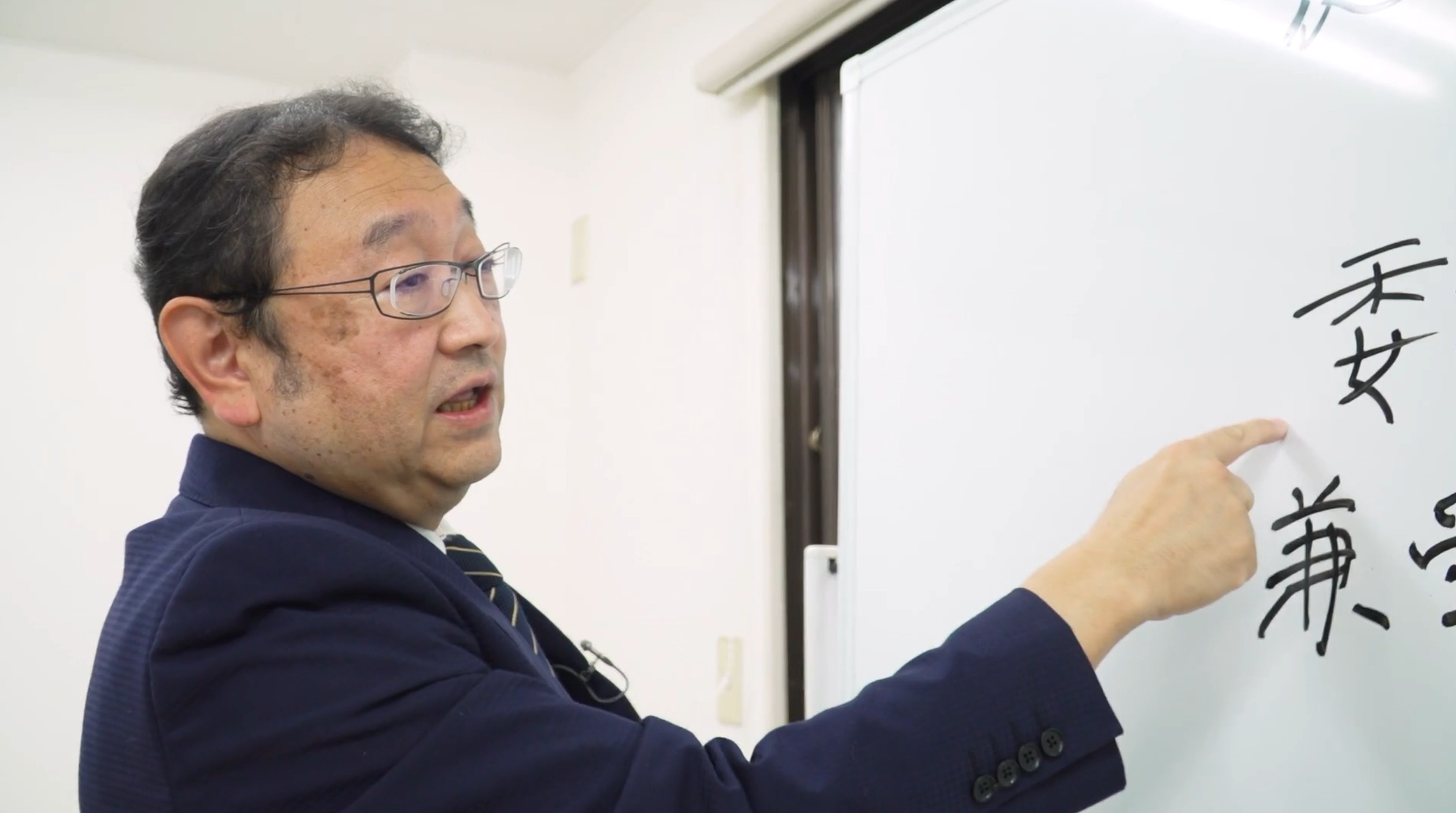 ホワイトボードで相続の仕組みを説明する新井さん
