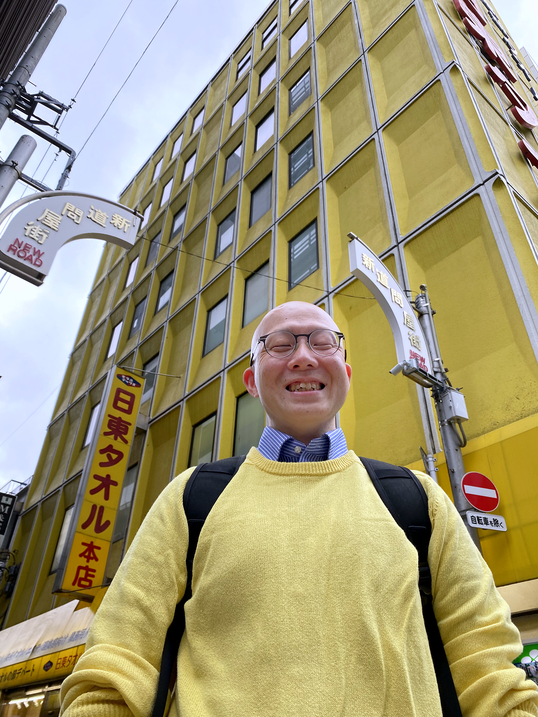 創業の地に立つ日東タオル本店の黄色いビルと鳥山さん