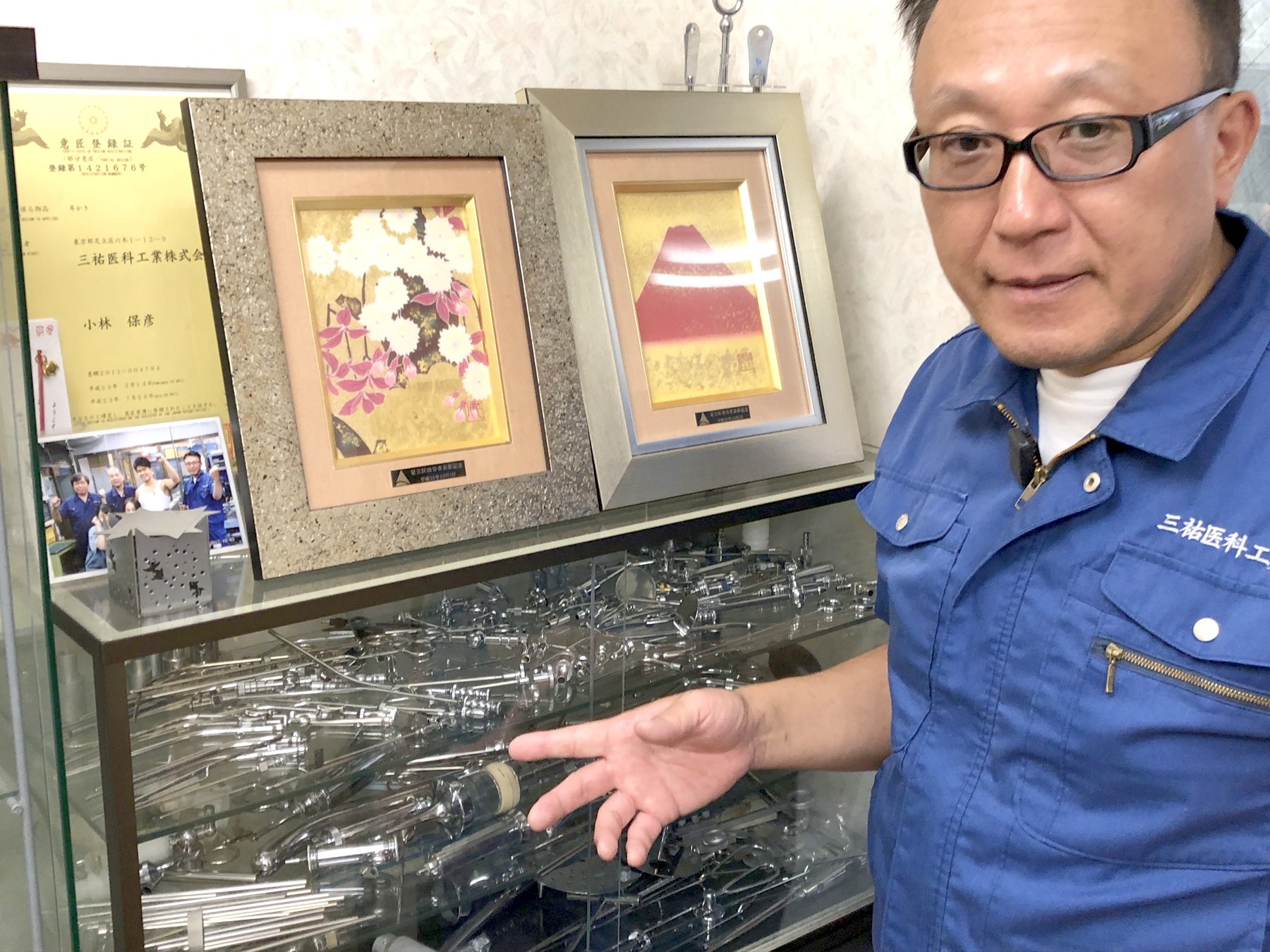 医療器具のガラスケースの前で、製品を手で示しながら説明する小林さん