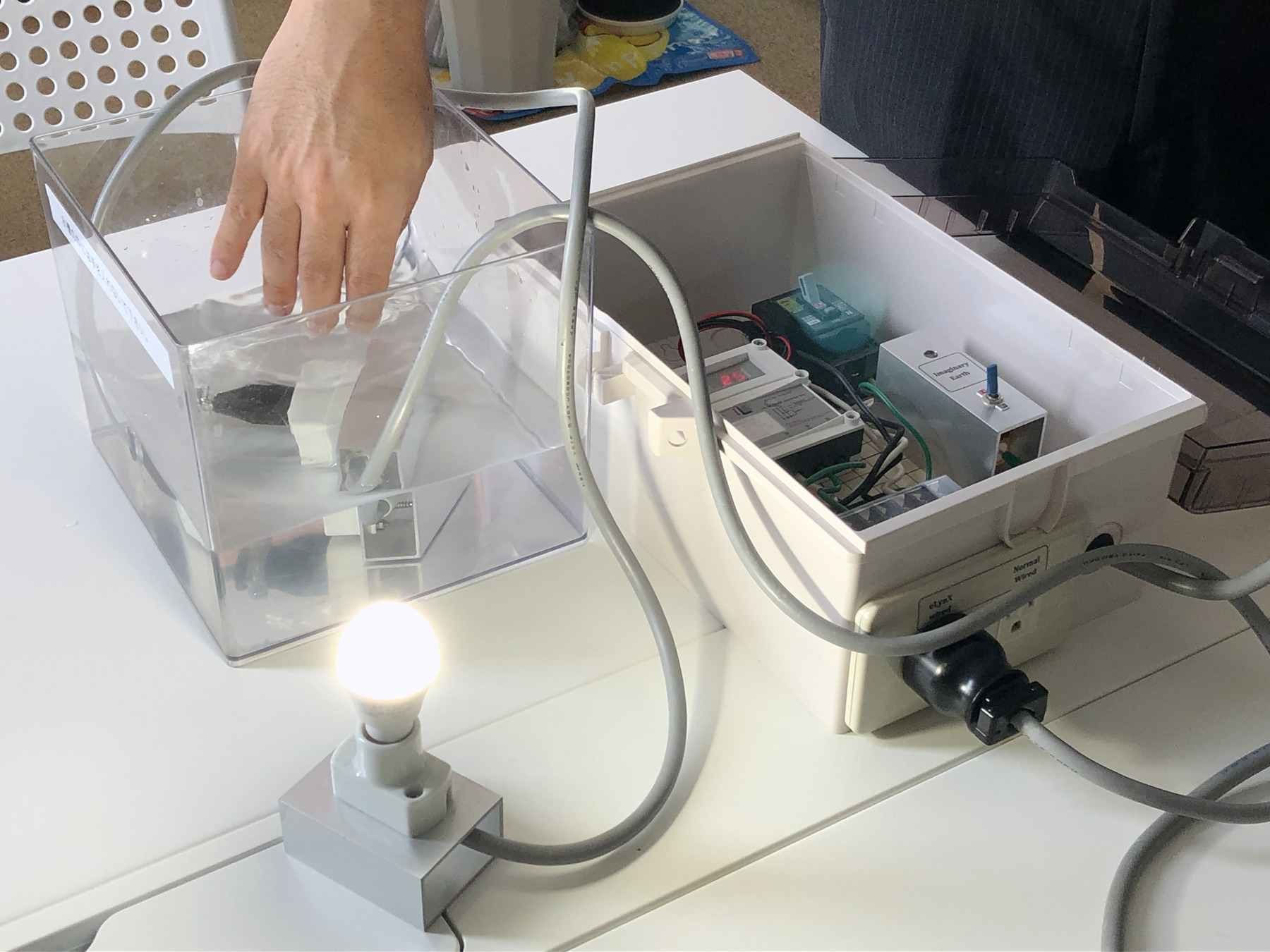 水のケースに手を入れても電球が消えない、装置のデモの様子